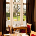 Dining tables with garden views in The Brasserie restaurant at Mercure Bradford Bankfield Hotel