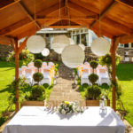 Close up shot of the wooden gazebo and hanging decorations of a wedding taking place in the luscious green garden at mercure bradford bankfield hotel