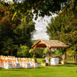 Wide shot of a wedding ceremony taking place in the luscious green garden at mercure bradford bankfield hotel